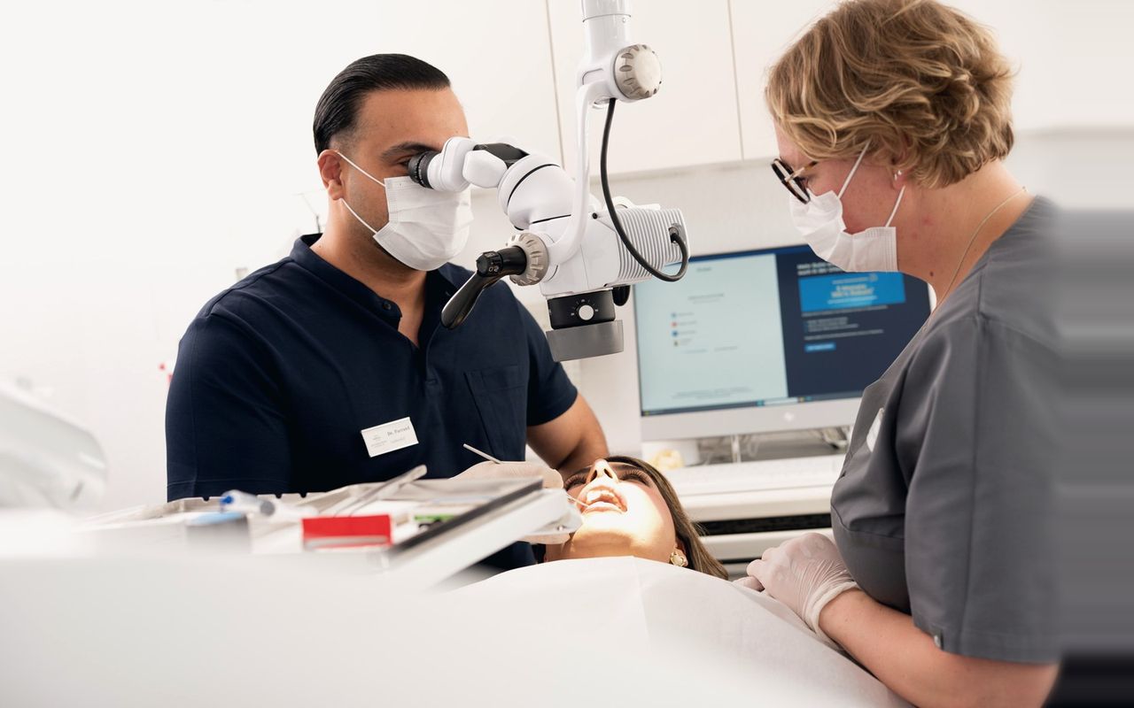 Dr. Ali Parrand behandelt unter dem Operationsmikroskop, assistiert von einer Mitarbeiterin