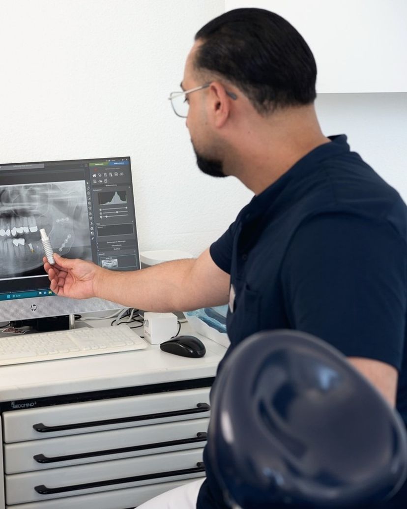 Dr. Ali Parrand zeigt ein Implantatmodell am Röntgenbild